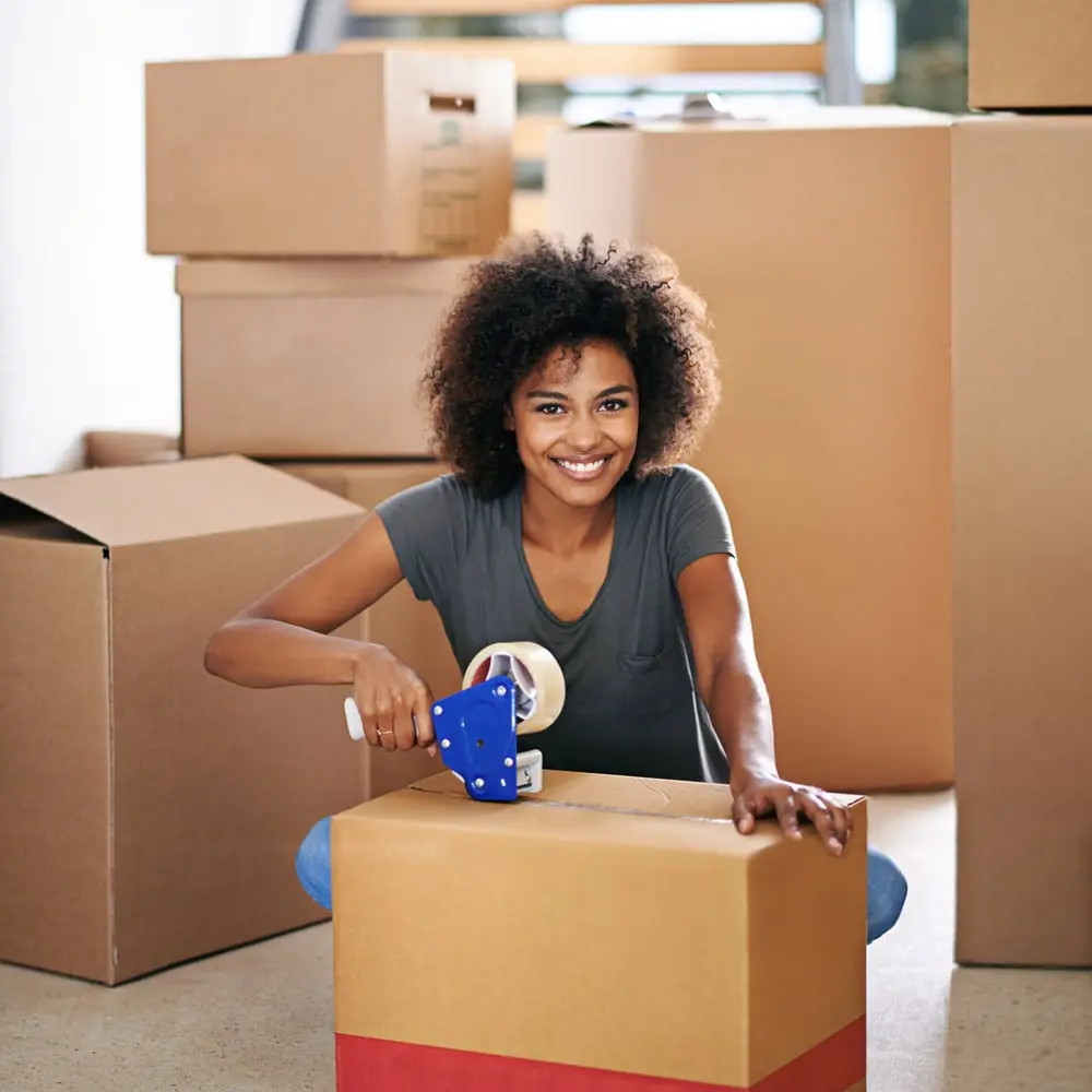 Woman putting packing tape on a moving box min